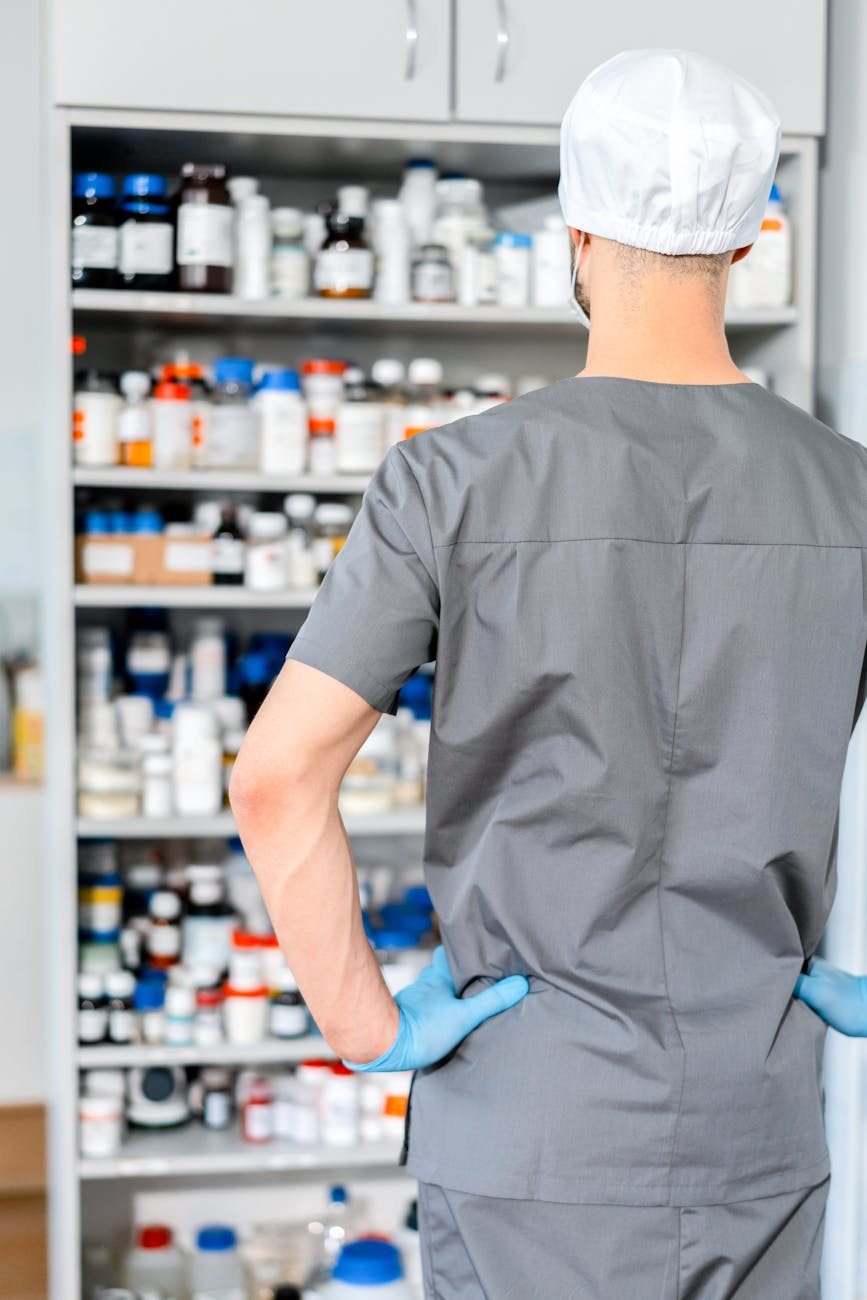 back view of a pharmacist standing in front of a cabinet full of medication