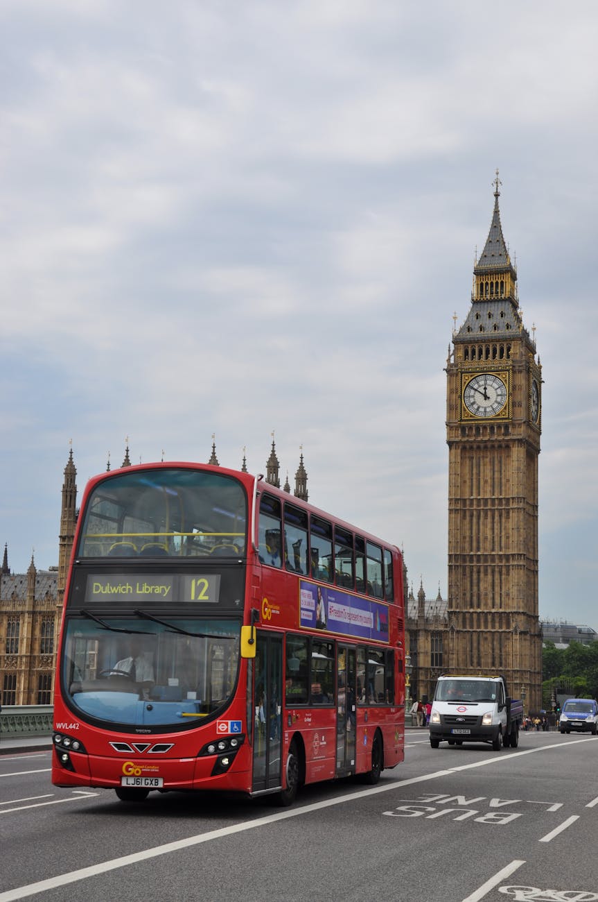 a double decker bus traveling on the road across the famous big ben