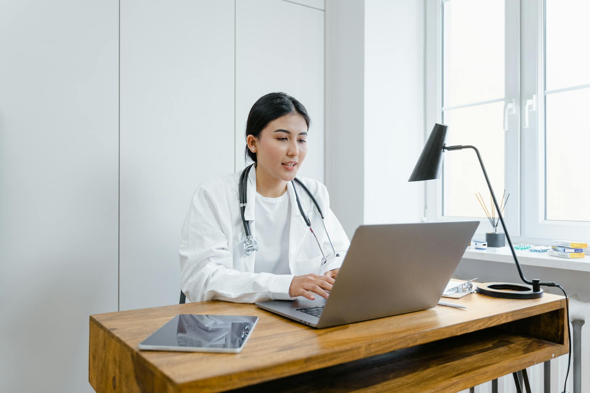 a woman in white coat using a macbook