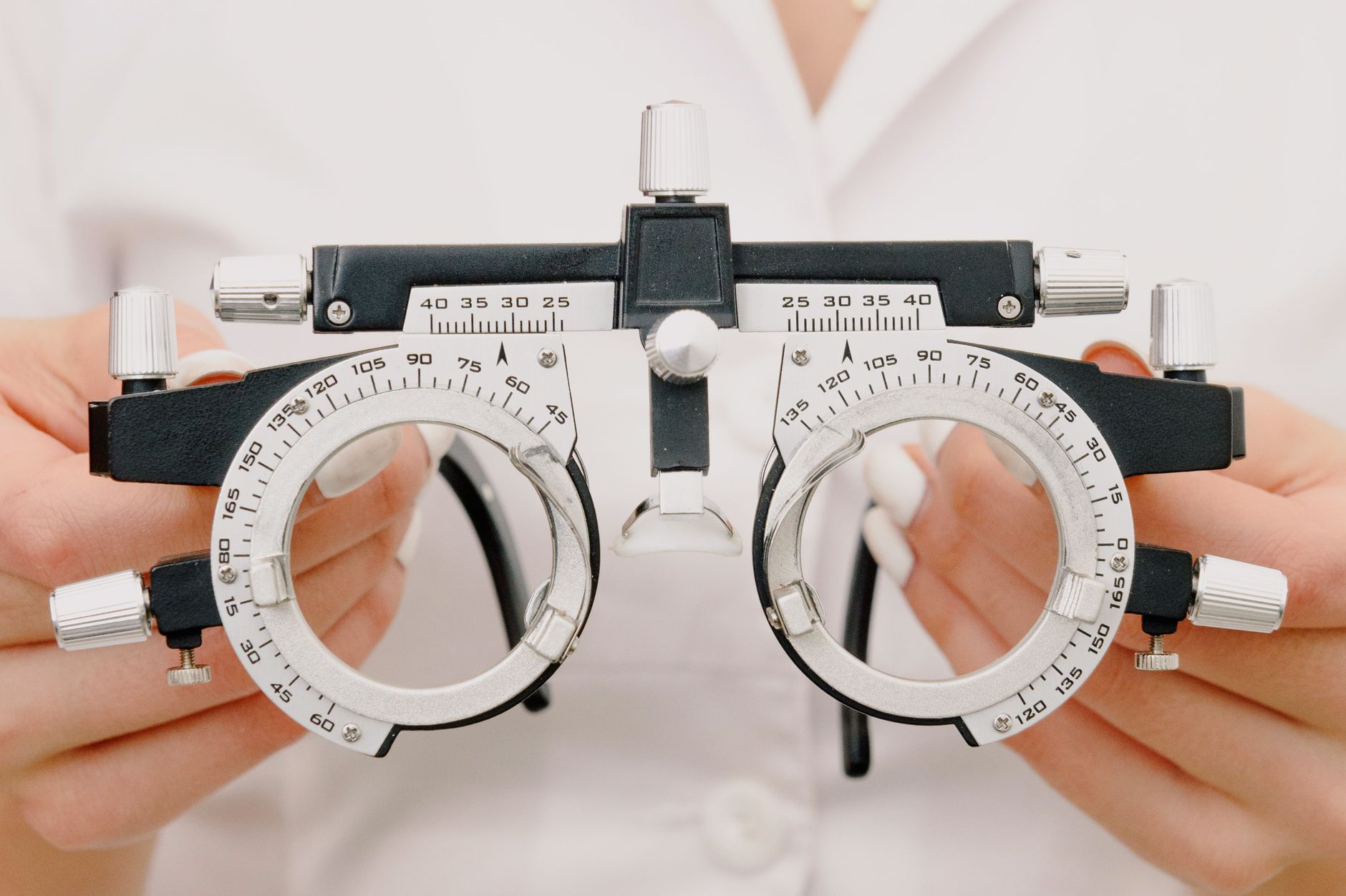crop unrecognizable female optometrist with trial frame in hands