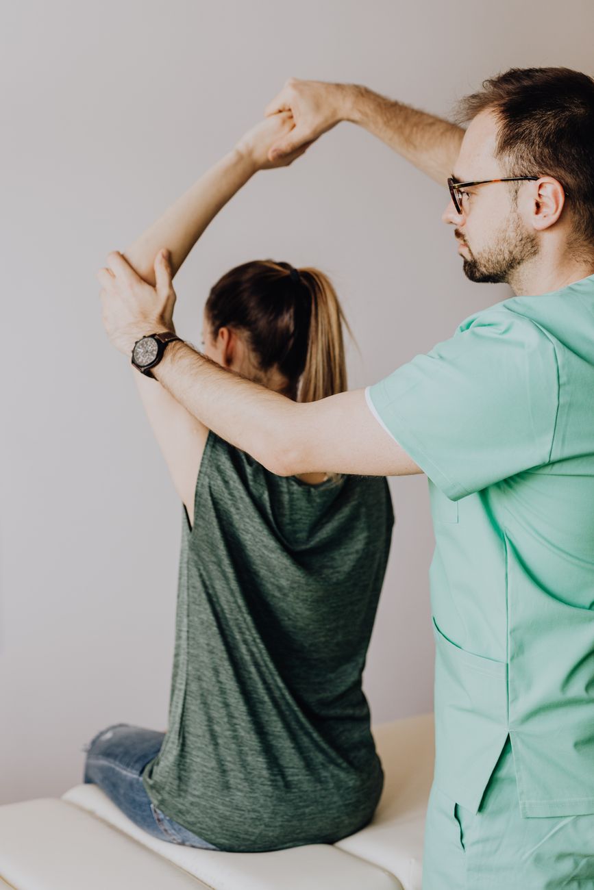 crop orthopedist examining arm of faceless female patient in clinic